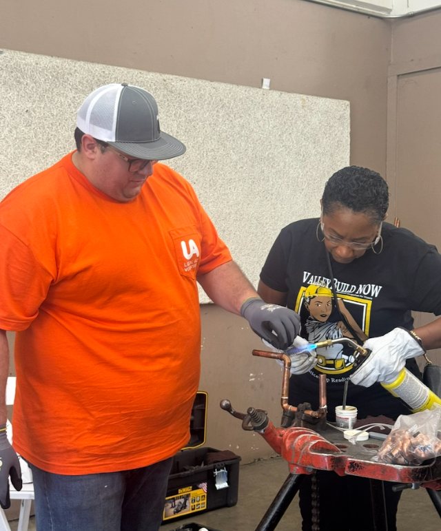 Ronna Green working alongside a tradesman at a high school youth day